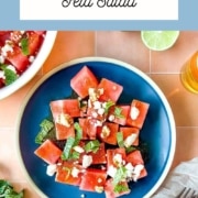 Watermelon salad on a peach tile background with the words watermelon mojito salad and the wed address two cloves kitchen dot com.