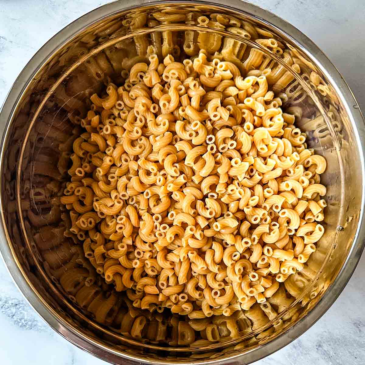 Cooked whole wheat pasta in metal bowl.