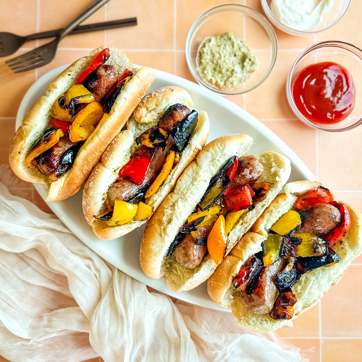 Overhead shot of sausage and peppers sandwiches on a white platter.
