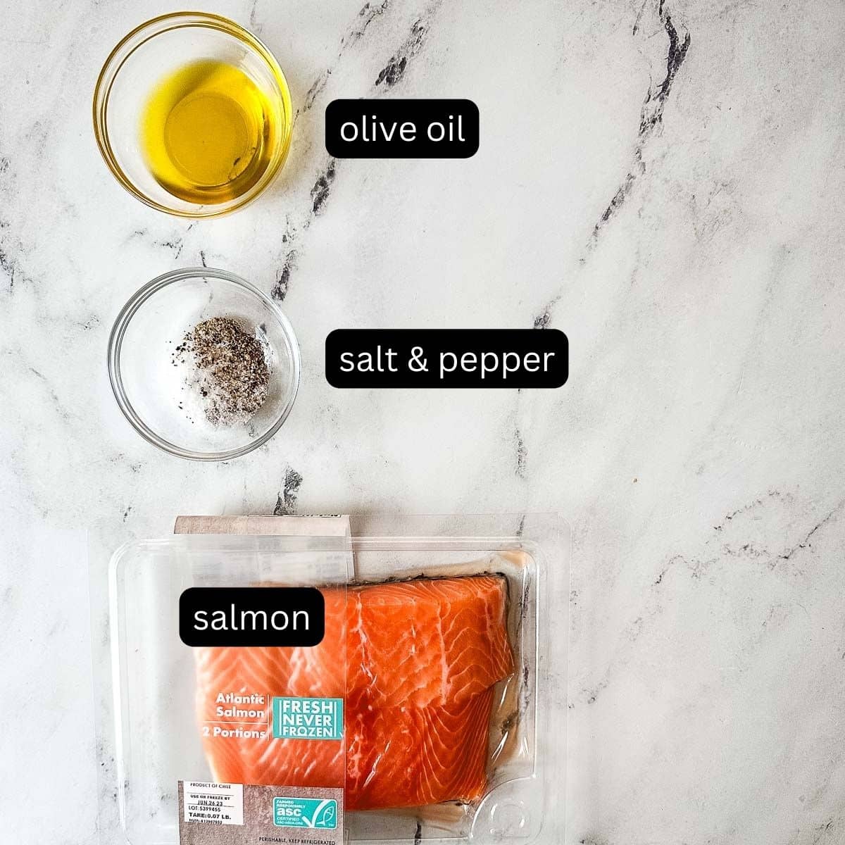 Labeled ingredients for pan-seared salmon on a white marble counter.