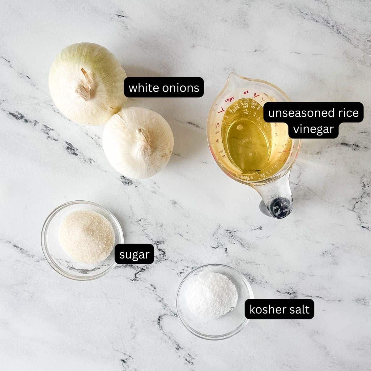 Labeled ingredients for pickled white onions on a white marble counter.