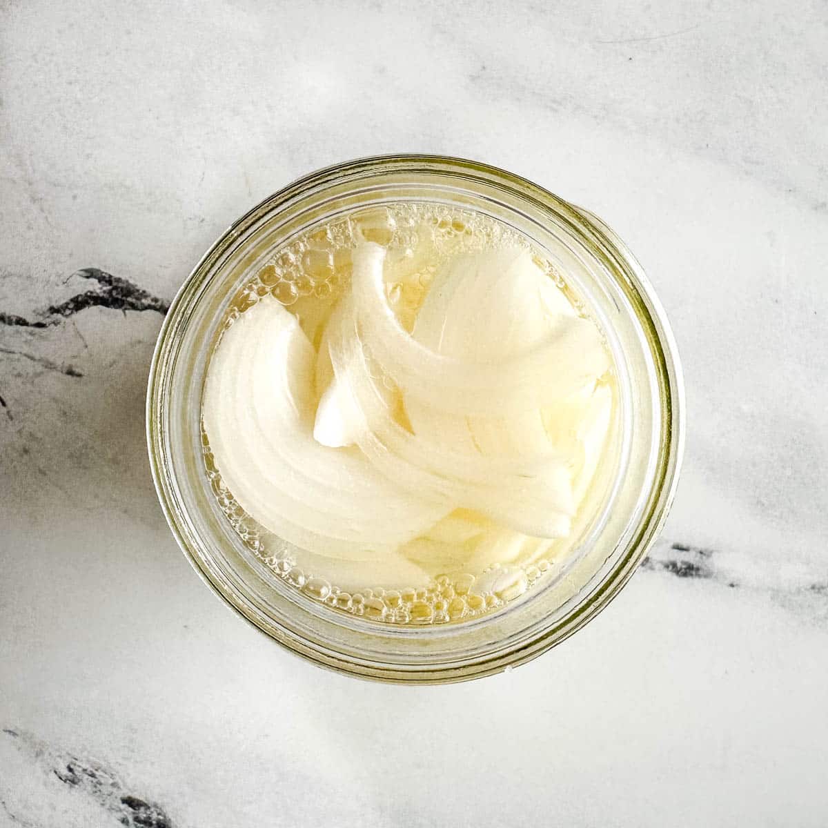 Pickled white onions in a glass jar.