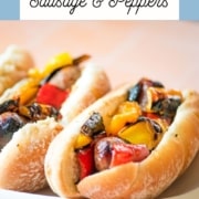 Grilled sausage and peppers sandwiches on a white platter.
