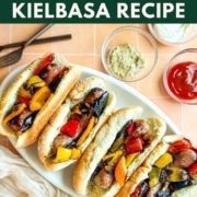 Grilled sausage and bell pepper sandwiches on a white platter.