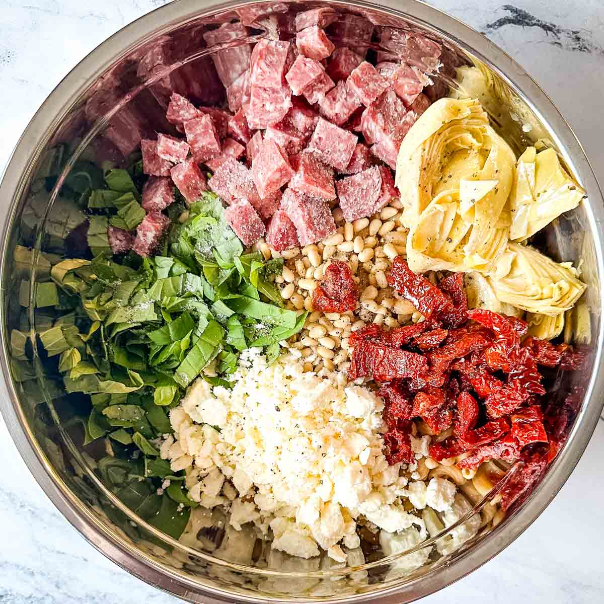 Ingredients for whole wheat pasta salad in a metal bowl.