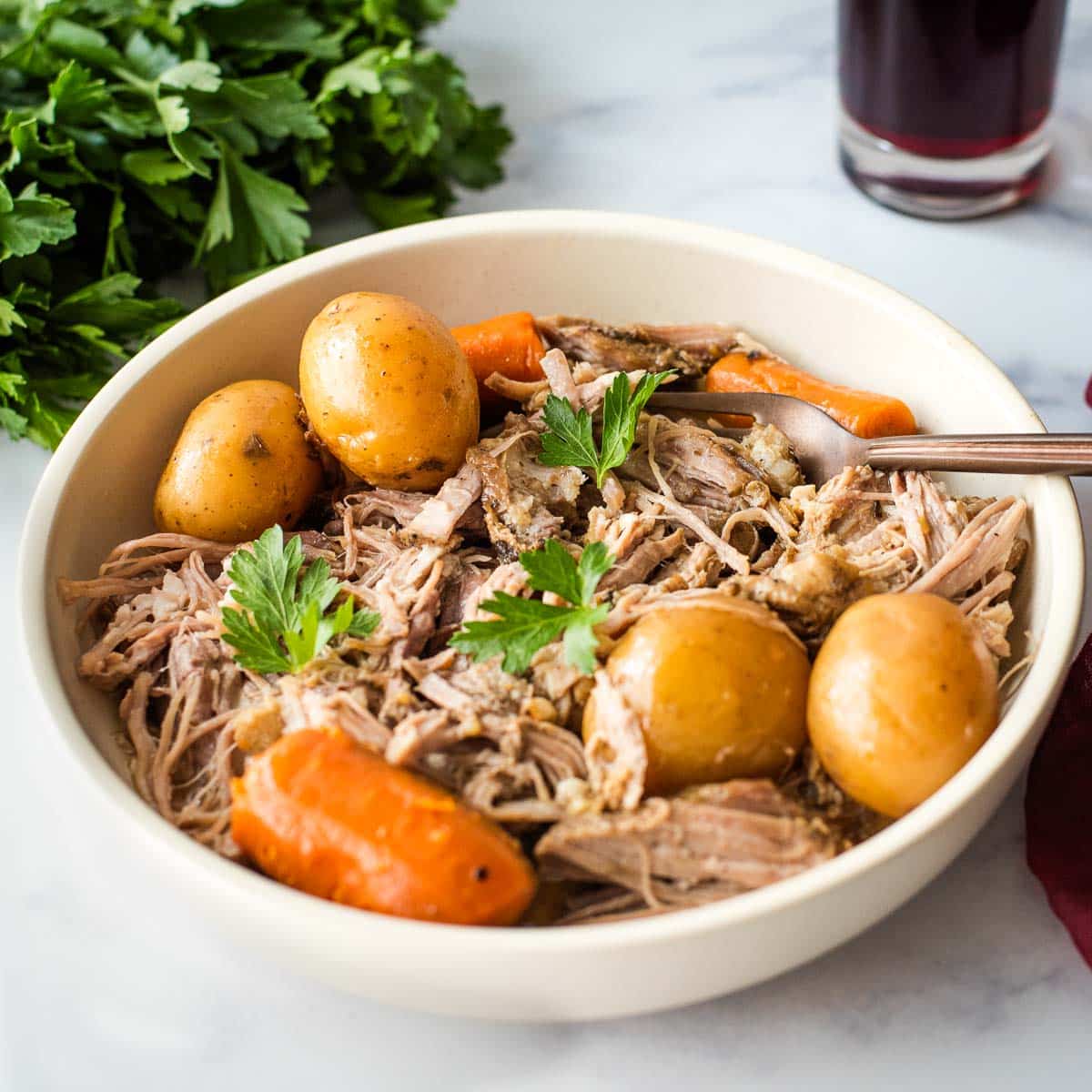 A bowl of roast pork with potatoes and carrots.