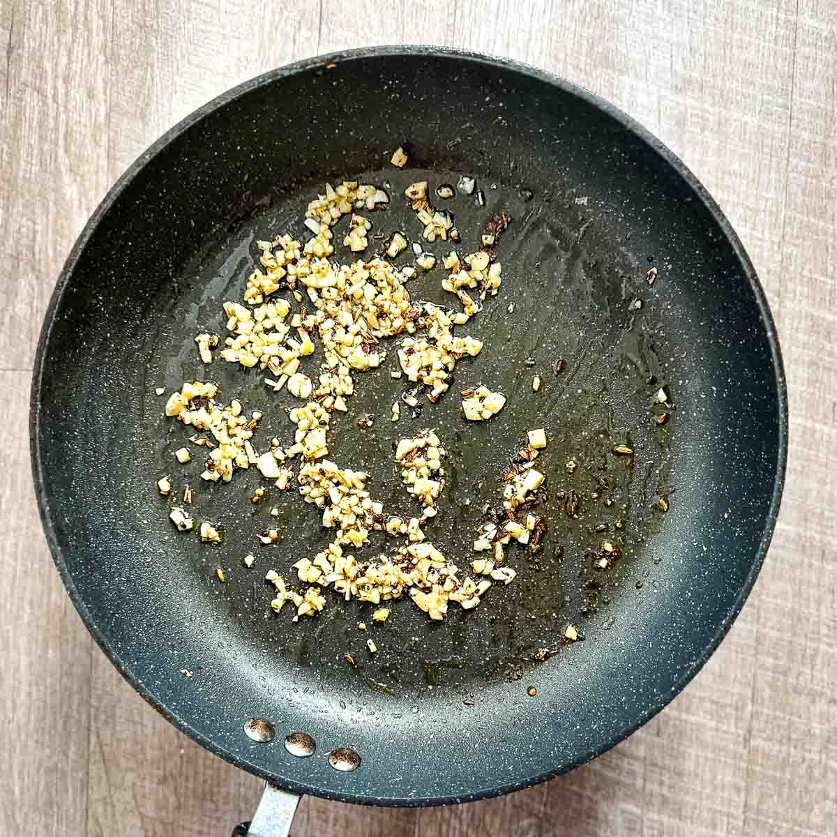 Garlic cooking in oil in a frying pan.
