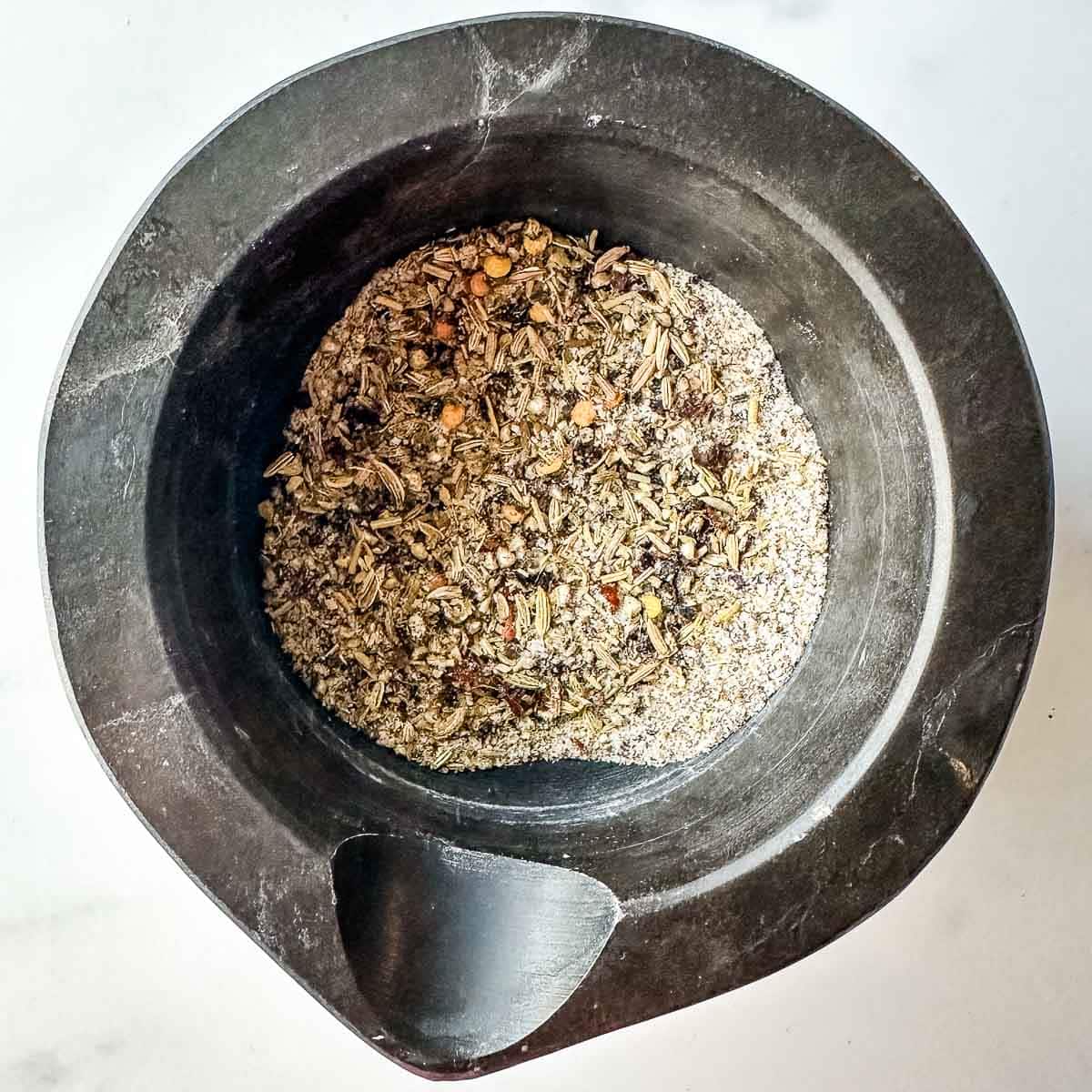 A mortar filled with ground herbs and spices.