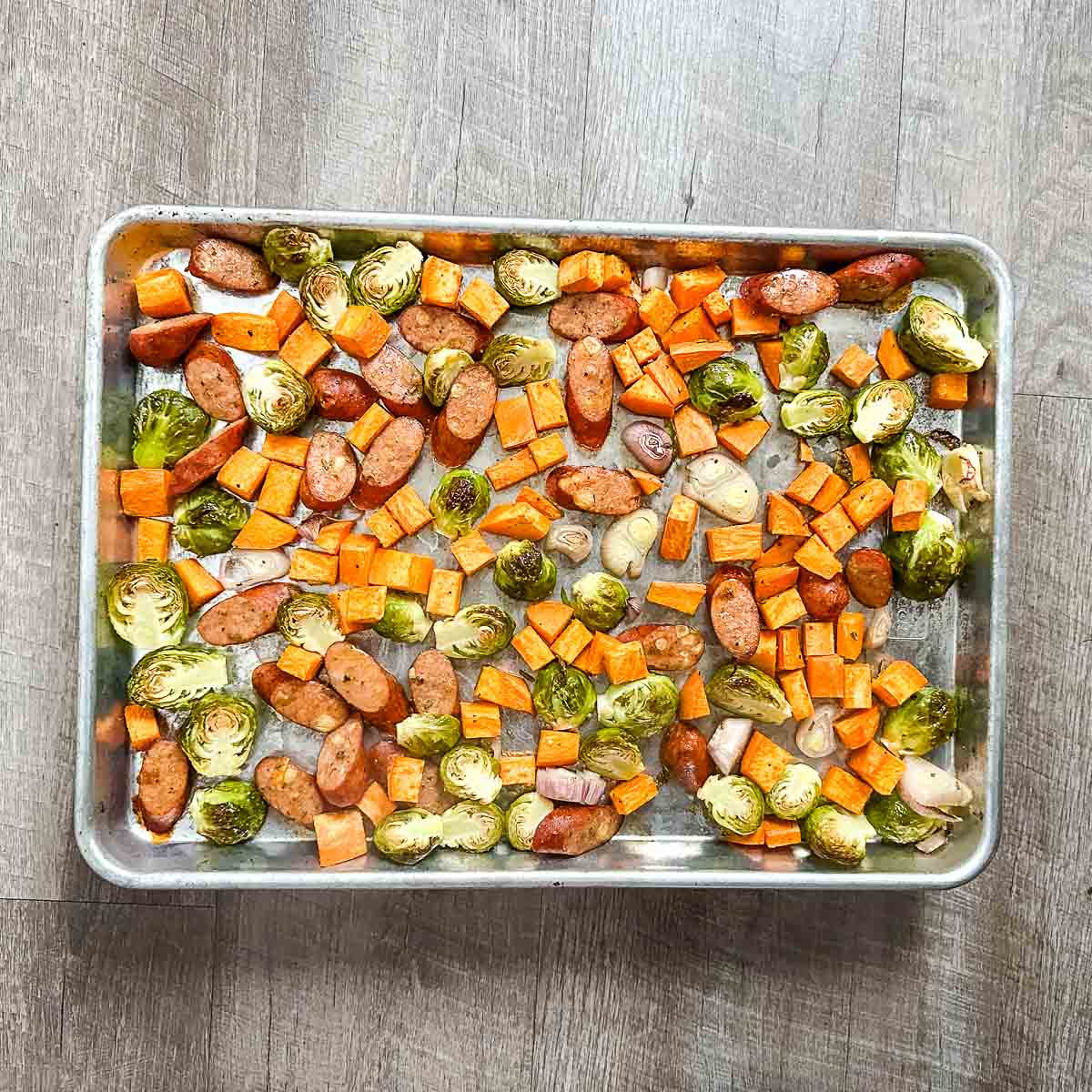 The completed harvest sheet pan dinner is shown on a wooden background.