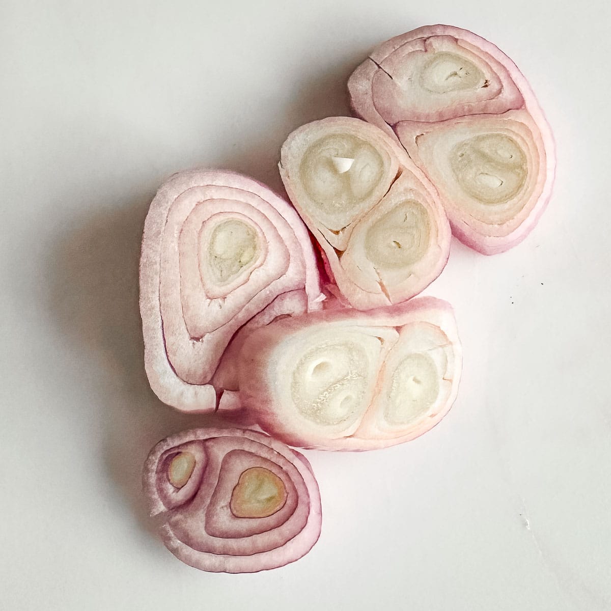 Sliced shallots on a white surface.