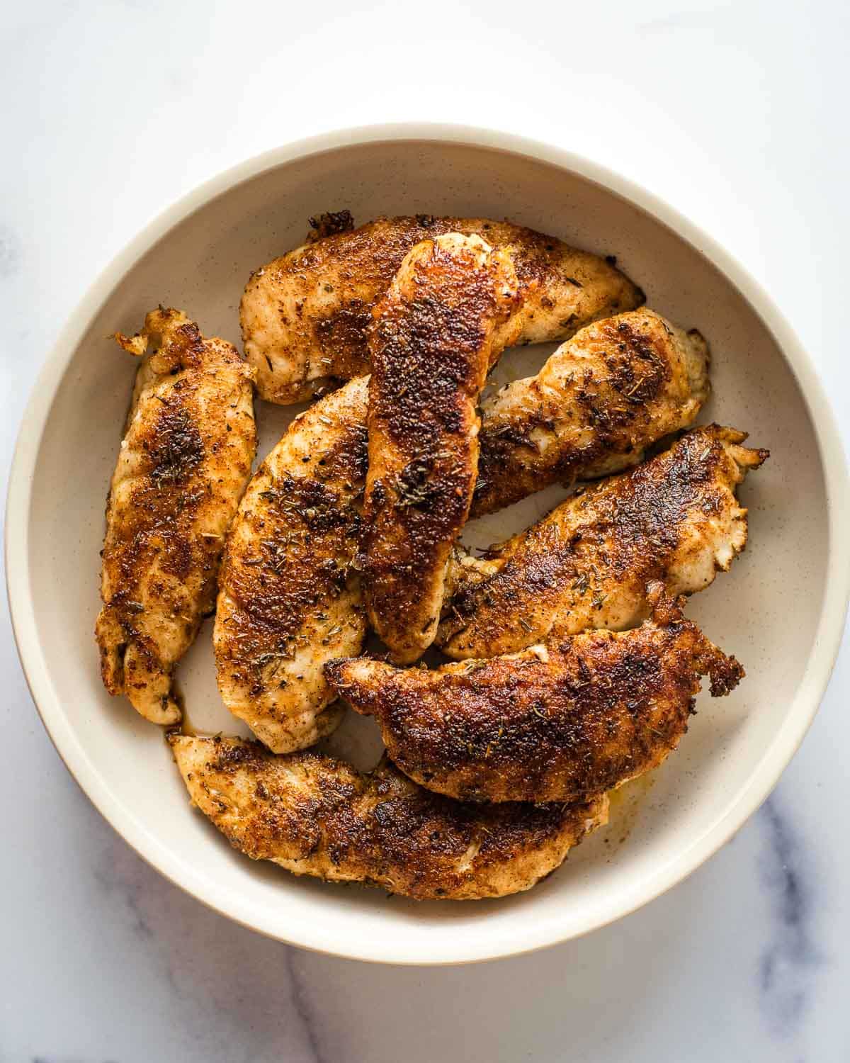 Blackened chicken tenders in a white bowl on a table.