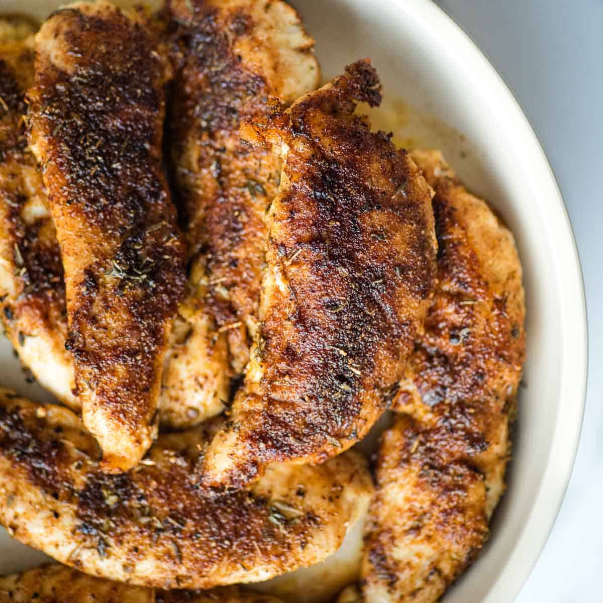 Blackened chicken tenders in a white dish.