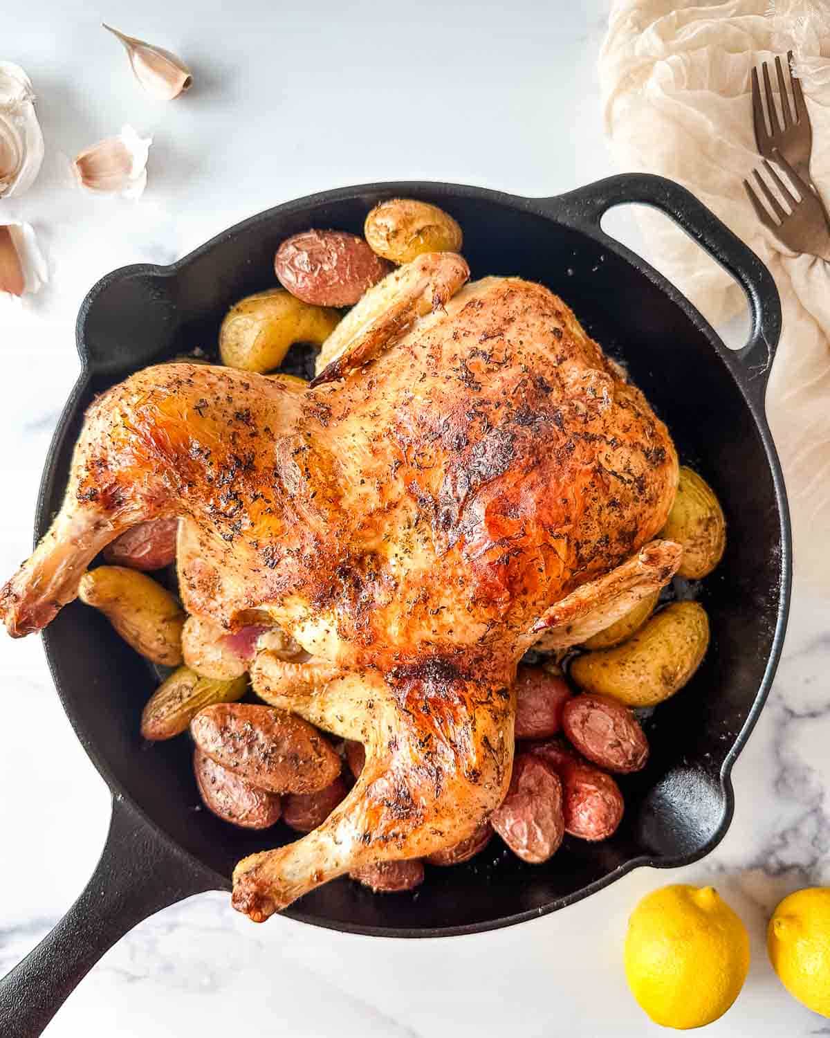 Greek roast chicken in a cast iron skillet with potatoes.