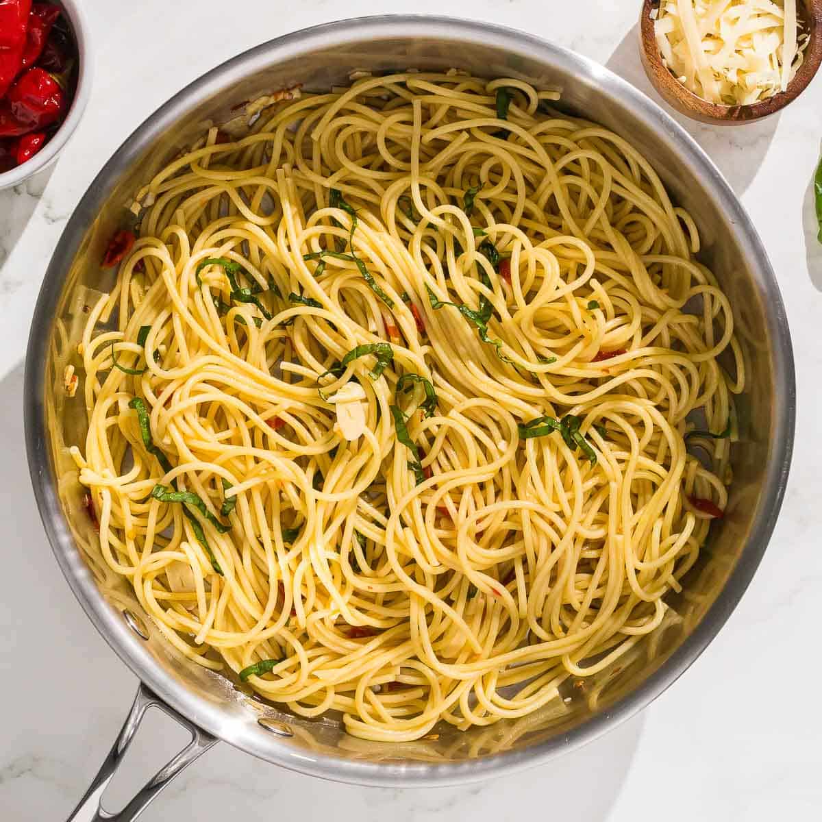 A pan of spaghetti with chilis, basil, and garlic.