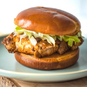 A chicken burger with coleslaw on a plate.