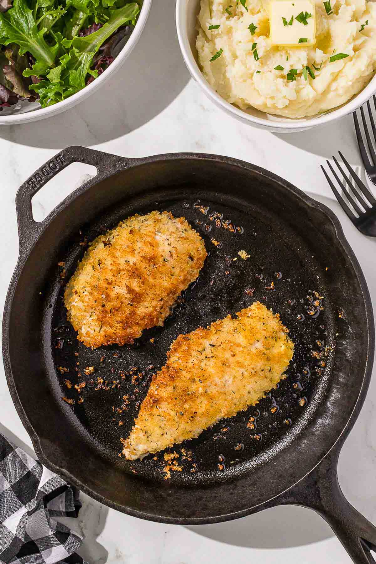 A cast iron skillet with Italian chicken cutlets.