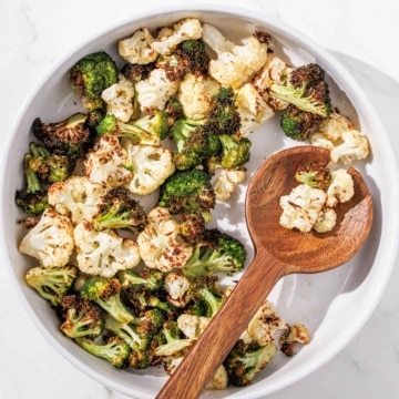 Air fryer broccoli and cauliflower with a wooden spoon.