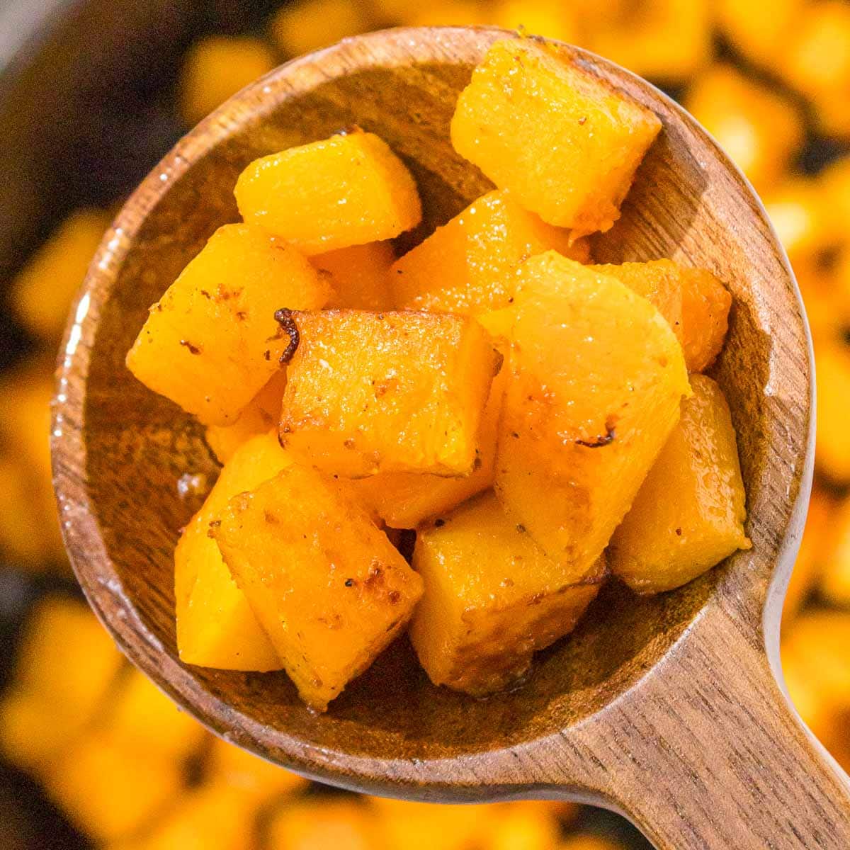 A wooden spoon filled with cubed butternut squash.