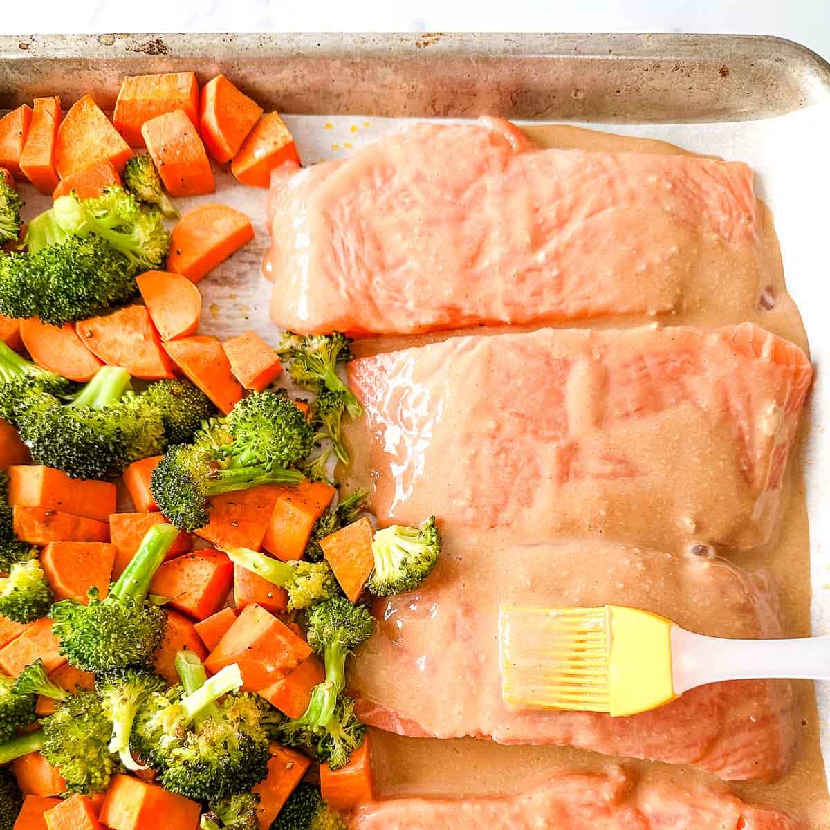 Maple dijon salmon is brushed with sauce beside cubed sweet potatoes and broccoli florets.