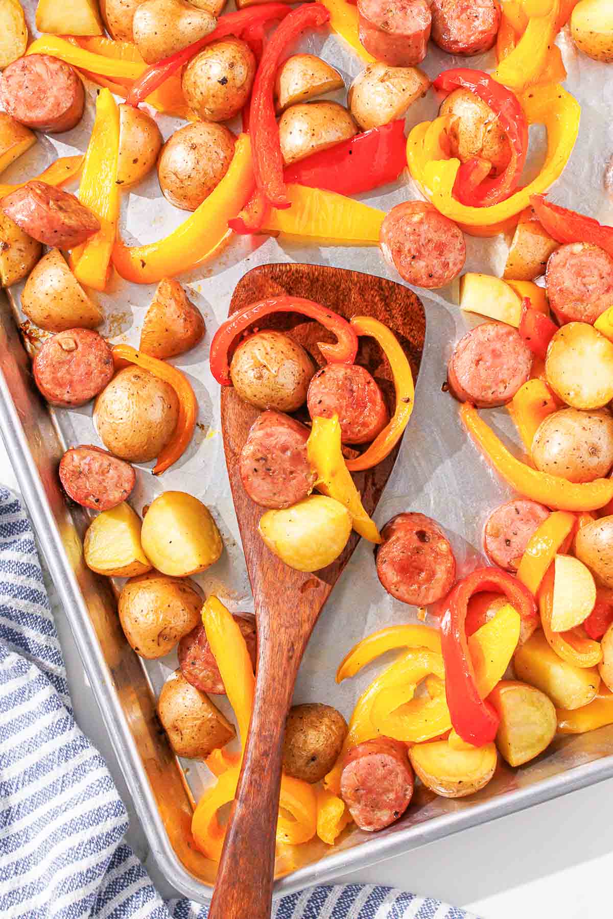 A baking sheet with potatoes, chicken sausage and peppers.
