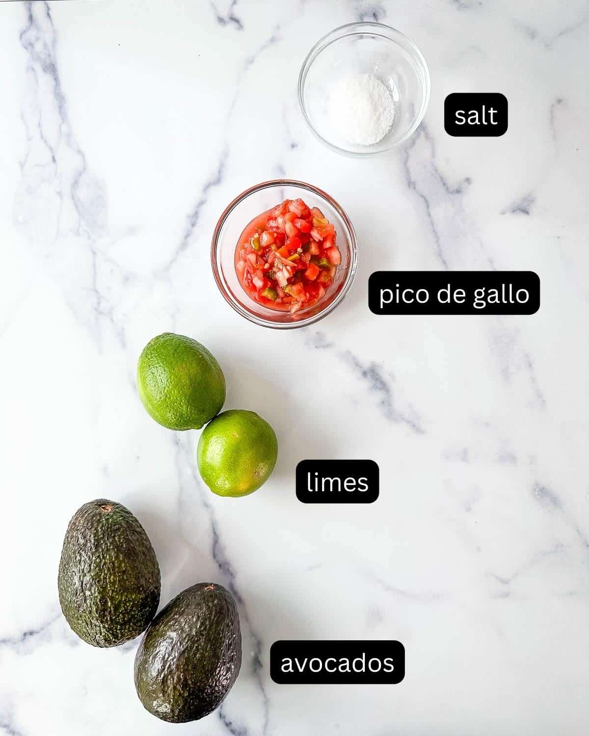 Ingredients for guacamole on a marble countertop.