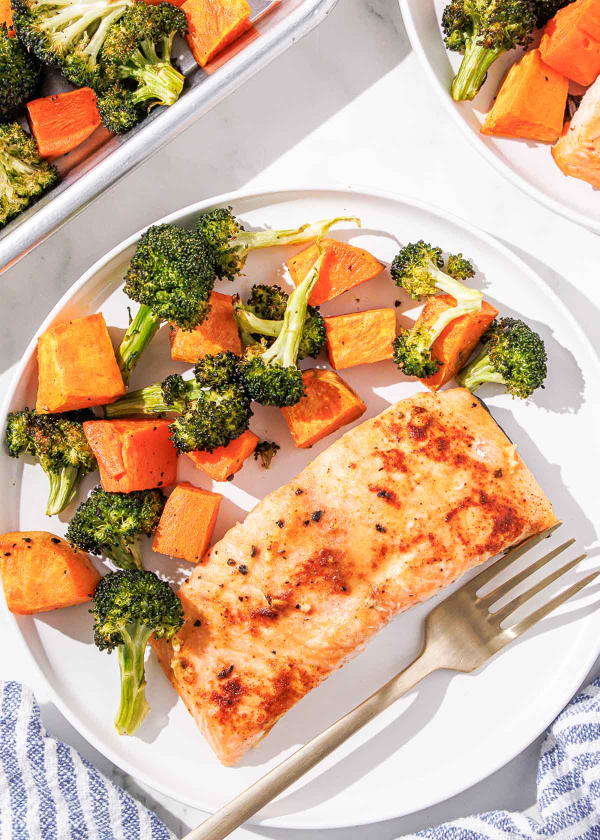 A plate of maple dijon salmon, sweet potatoes, and broccoli with a fork.