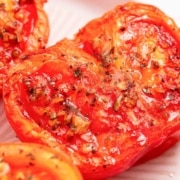 air fryer roasted tomatoes on a plate with herbs.