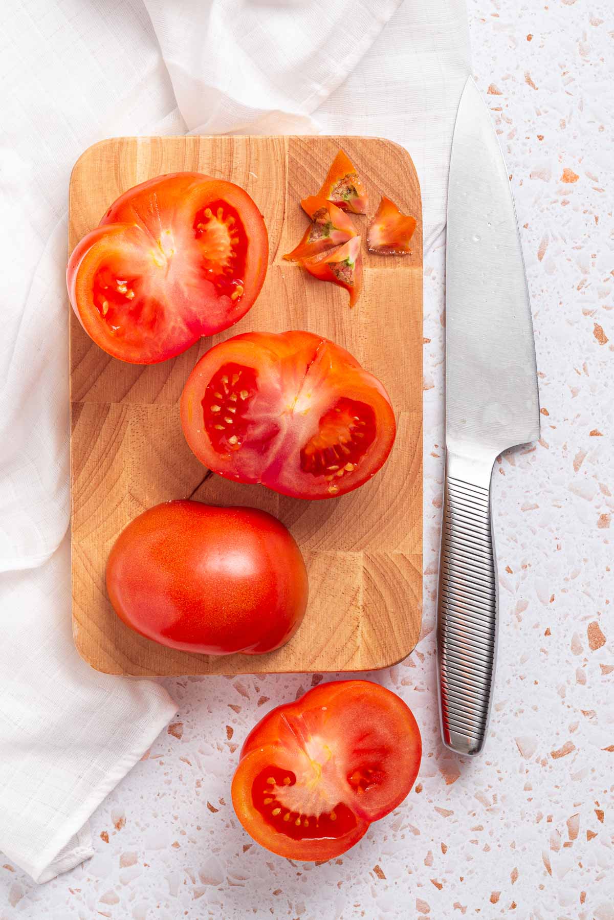 Sliced tomatoes and a knife on a cutting board.