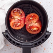 An air fryer with tomatoes in it.