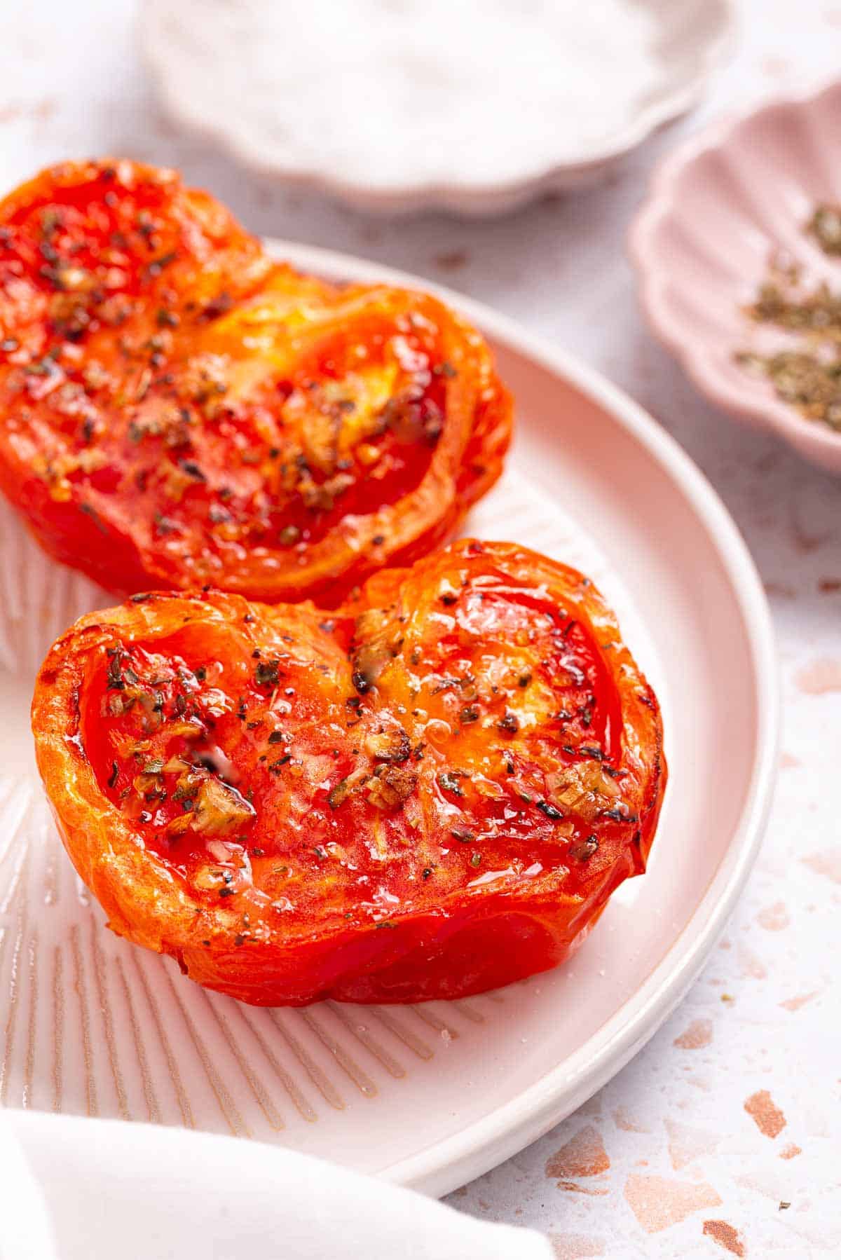 Two roasted tomatoes on a plate.