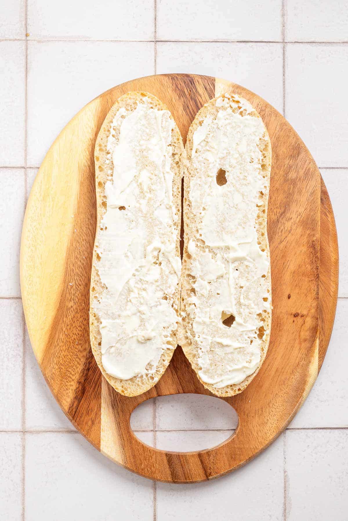 A bread with mayonnaise on a wooden board.