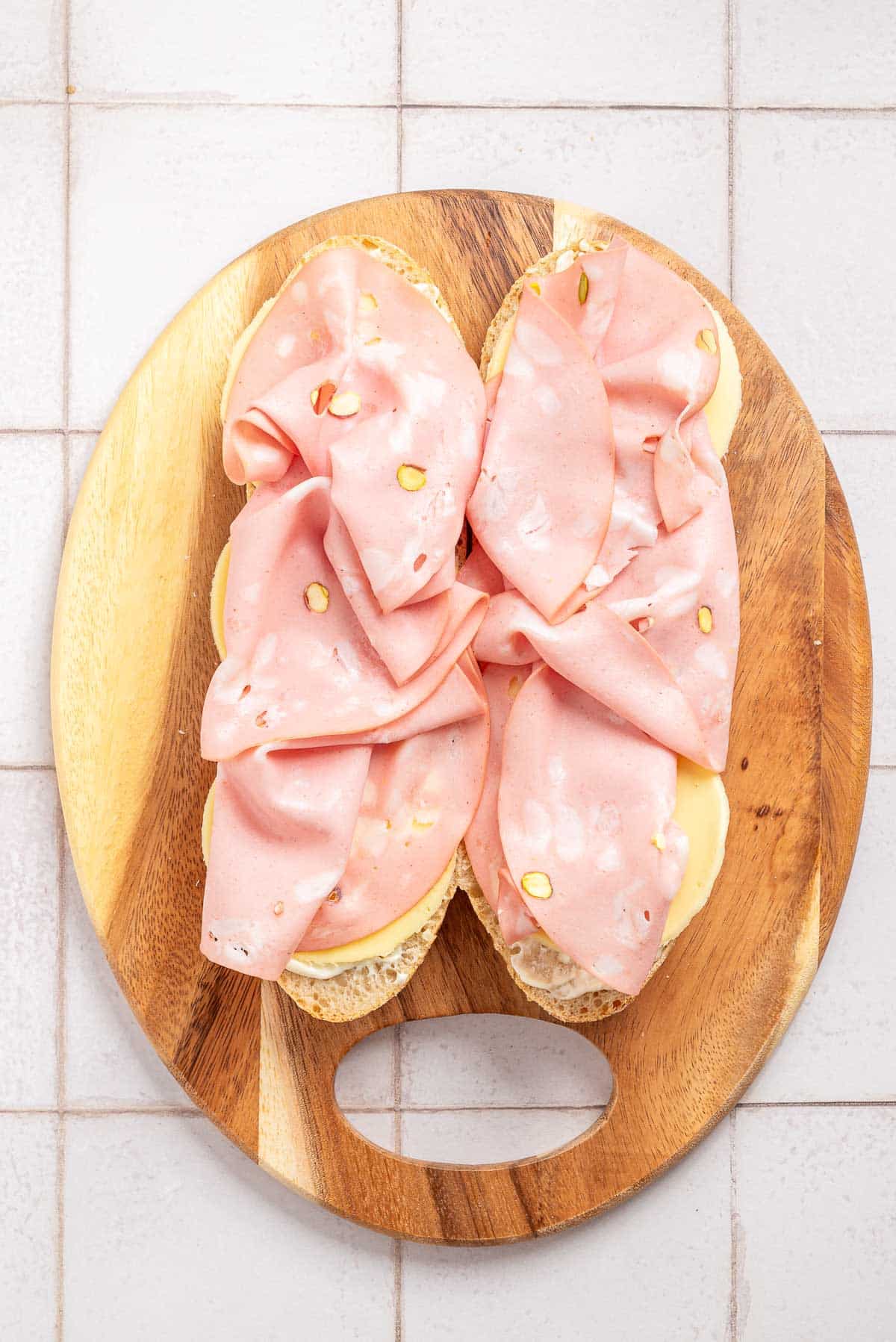 A sandwich with mortadella added on a wooden board.