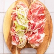 A sandwich with meat and lettuce on a wooden board.
