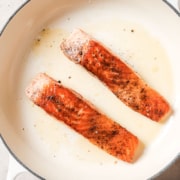 Two salmon fillets in a skillet.