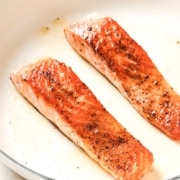 Two salmon fillets in a frying pan.