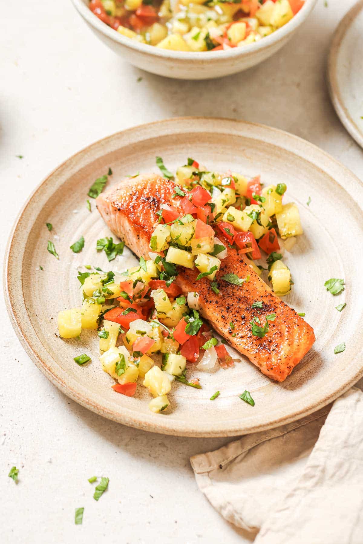 A plate with salmon and pineapple salsa.