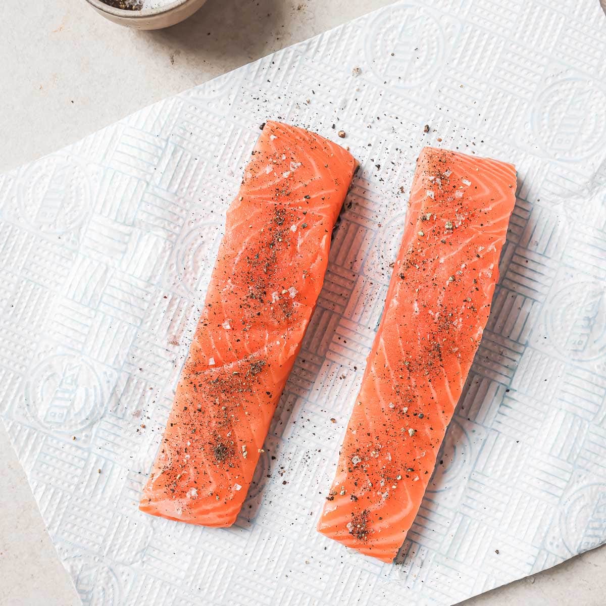 Two pieces of salmon on a paper towel.