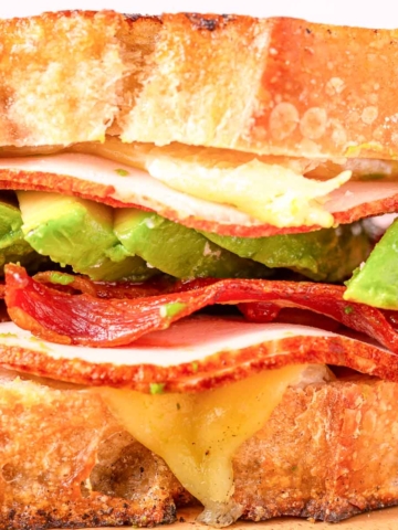 A turkey avocado sandwich sandwich with bacon and cheese.