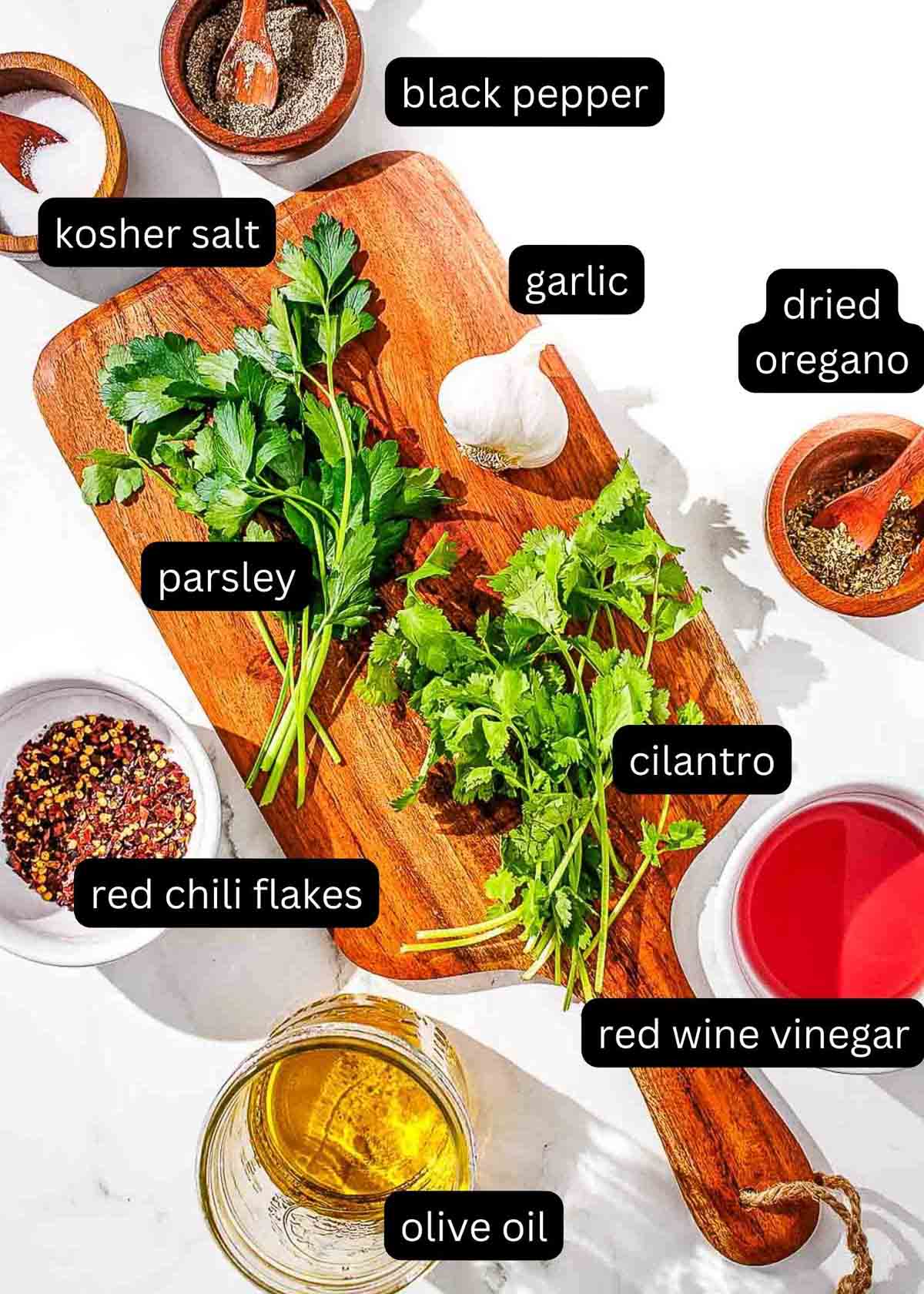 A cutting board with labeled ingredients for cilantro chimichurri.