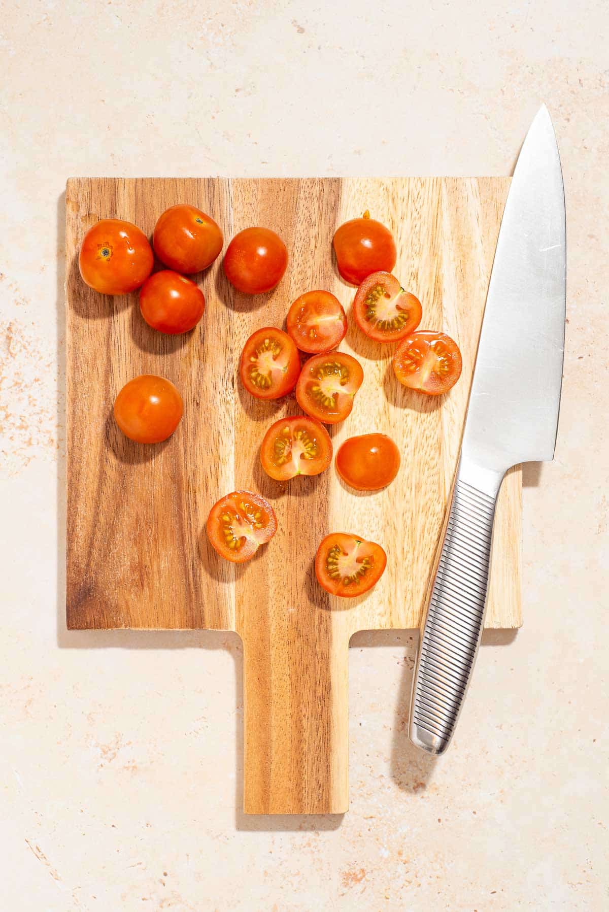 A cutting board with tomatoes and a knife.