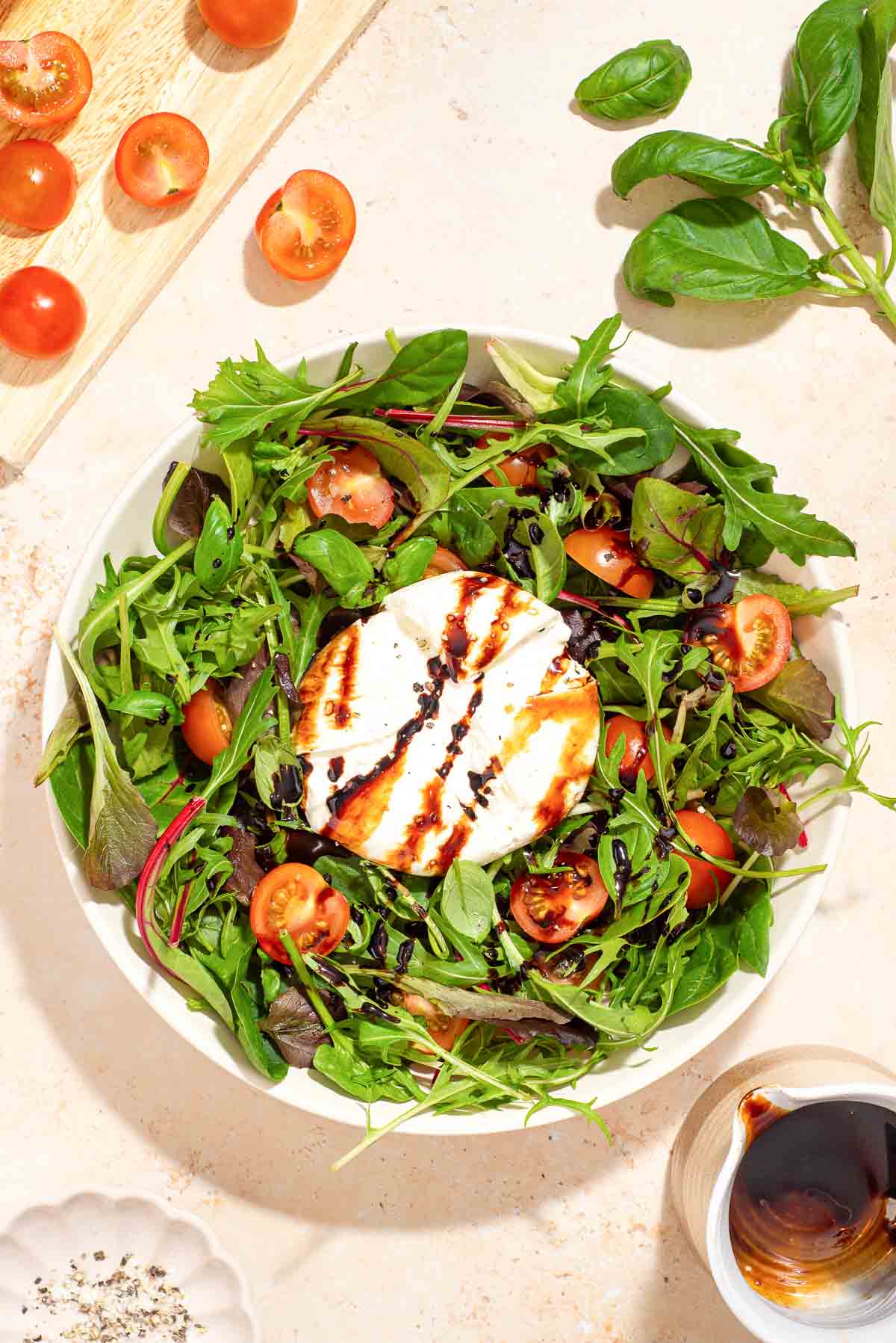 A white plate with a burrata caprese salad on it.