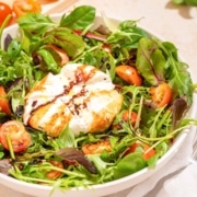 A white bowl with a burrata caprese salad in it.