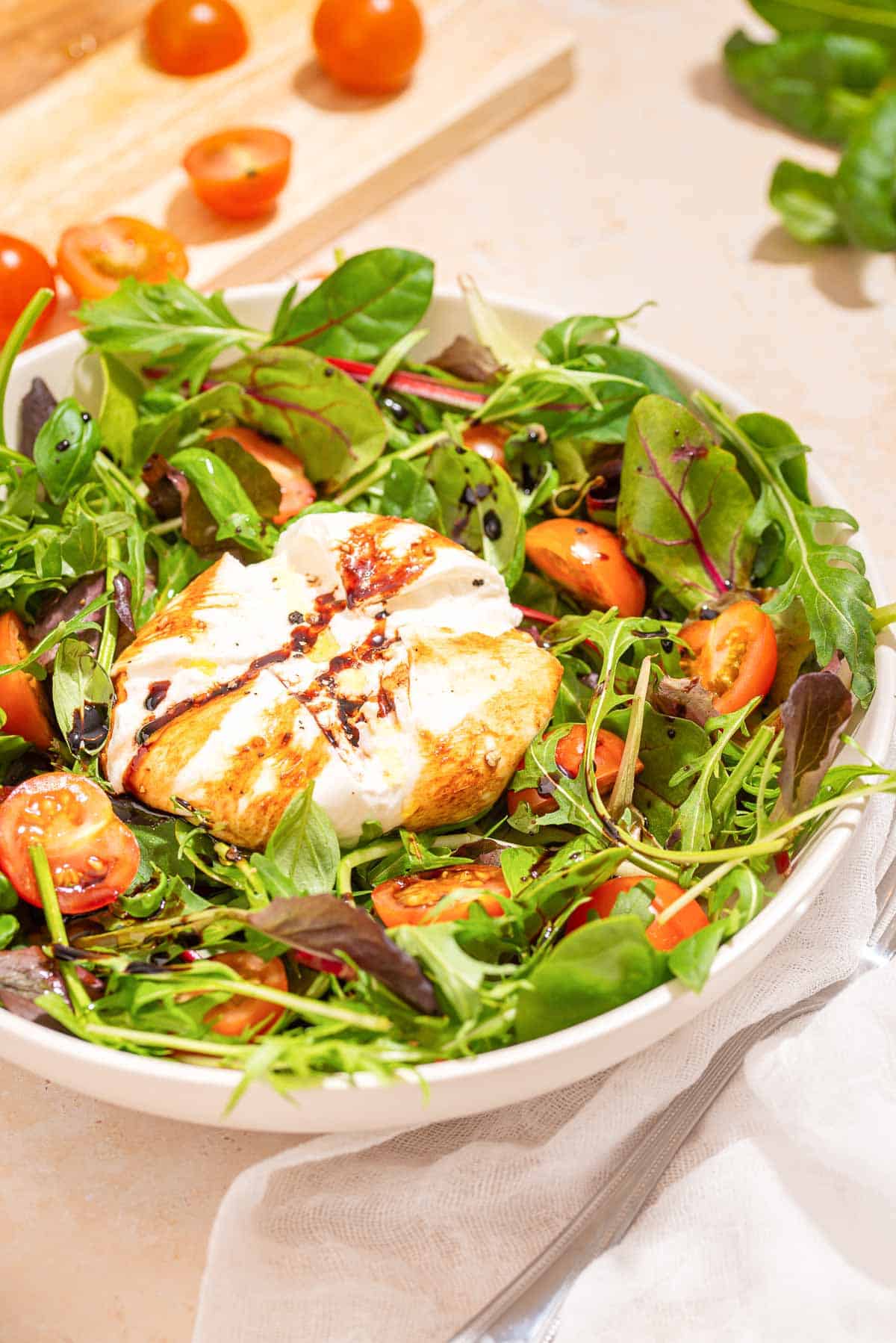 A white bowl with a burrata caprese salad in it.