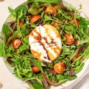 A salad with burrata, tomatoes and greens.