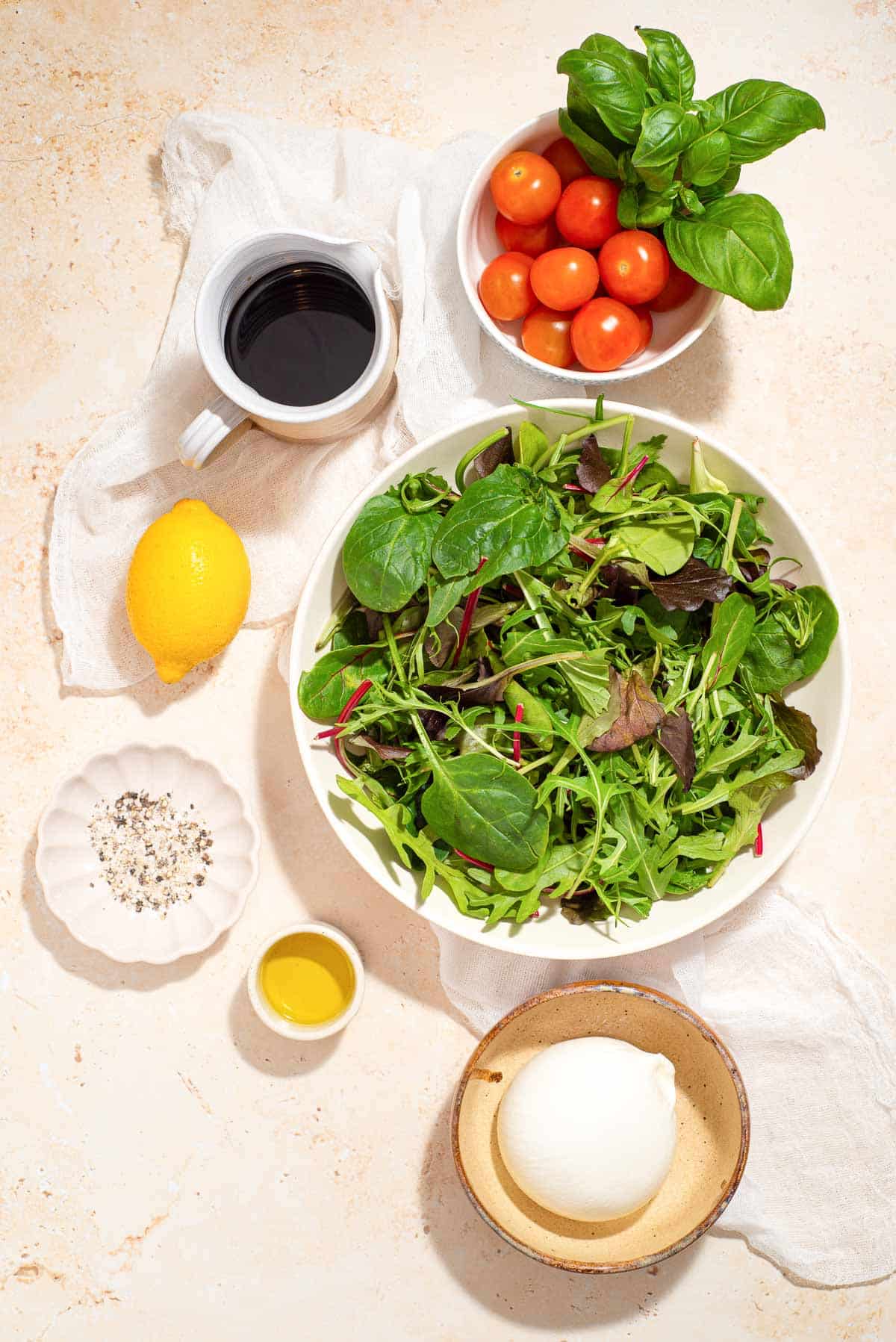 The ingredients for a burrata caprese salad are in a bowl on a table.