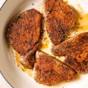 Blackened tuna steaks in a skillet on a table.