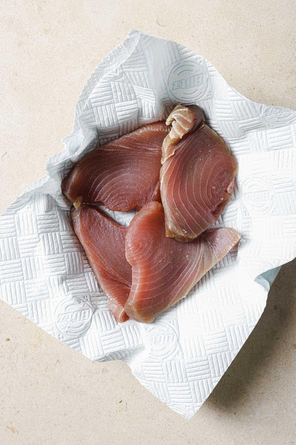 Tuna fillets are patted dry with paper towels.
