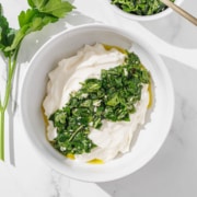 A bowl of chimichurri aioli surrounded by fresh parsley.