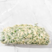 Chimichurri butter is rolled in a piece of plastic wrap.