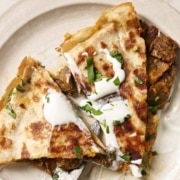 Quesadillas with meat and sour cream on a plate.